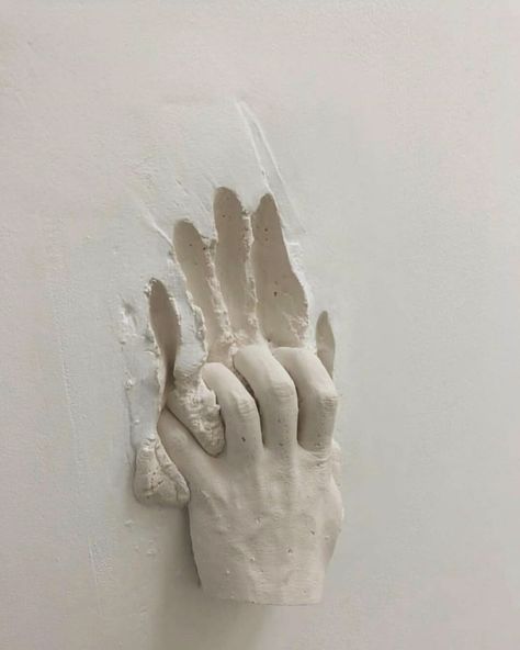 A sculpture depicting a hand gracefully holding a piece of paper, showcasing intricate details and artistic expression.