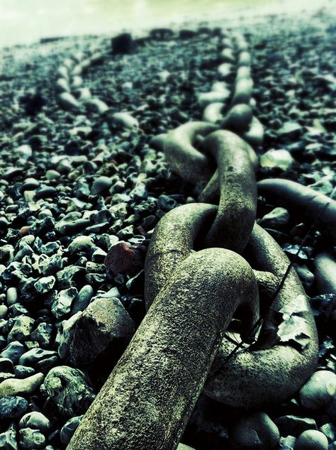 A chain rests on the ground beside a cluster of rocks.